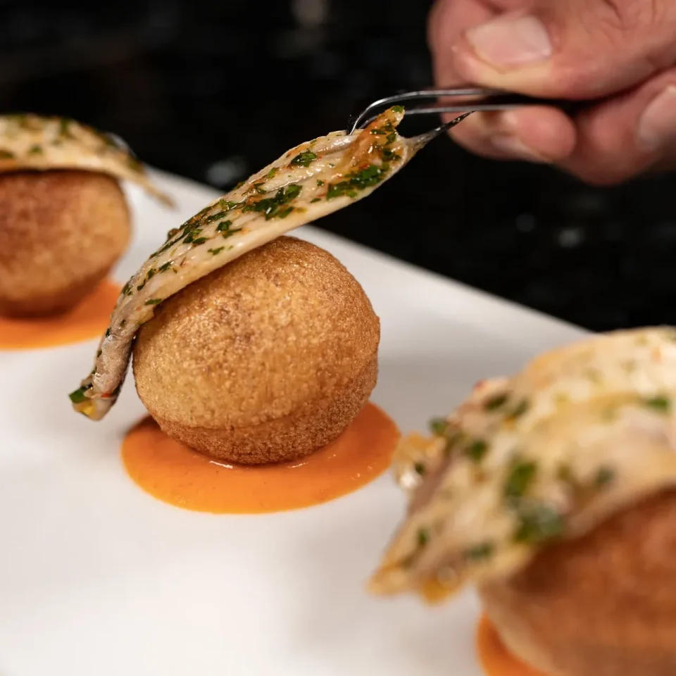 Bocado dorado del menú mediterráneo servido con salsa